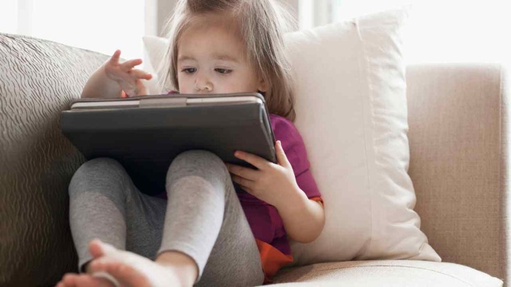 Una bambina sul divano gioca con iPad