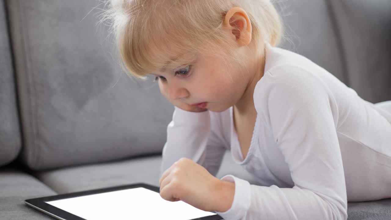 Bambino gioca con iPad sul divano