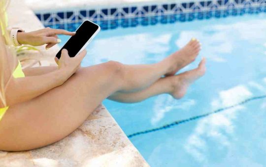 Giovane donna con smartphone in piscina